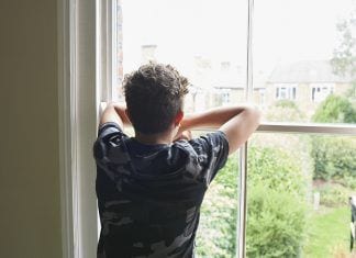 Teenage boy looking out of bedroom window