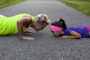 mom and daughter doing push ups on driveway