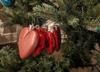 Three glitter heart ornaments on a Christmas tree.