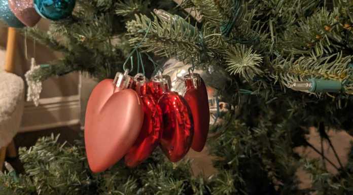 Three glitter heart ornaments on a Christmas tree.